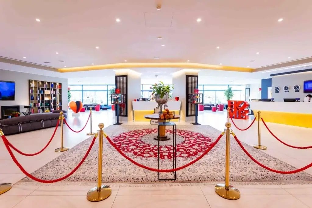 Lobby luminosa con reception design, tappeto rosso e aree lounge dell’an park hotel milano settala.